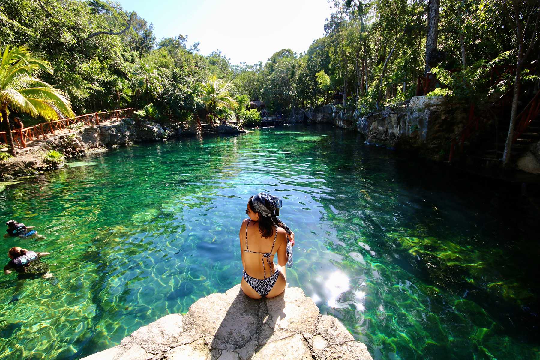 Traveler sitting at the edge of a jungle cenote near Playa del Carmen